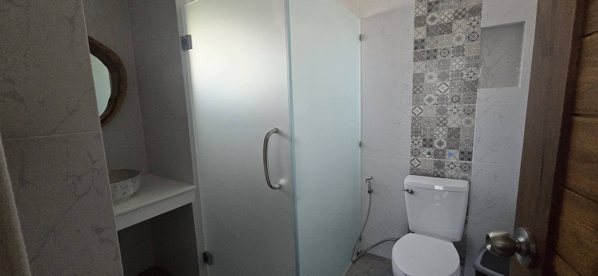 Bathroom with frosted-glass walk-in shower and decorative tile accent
