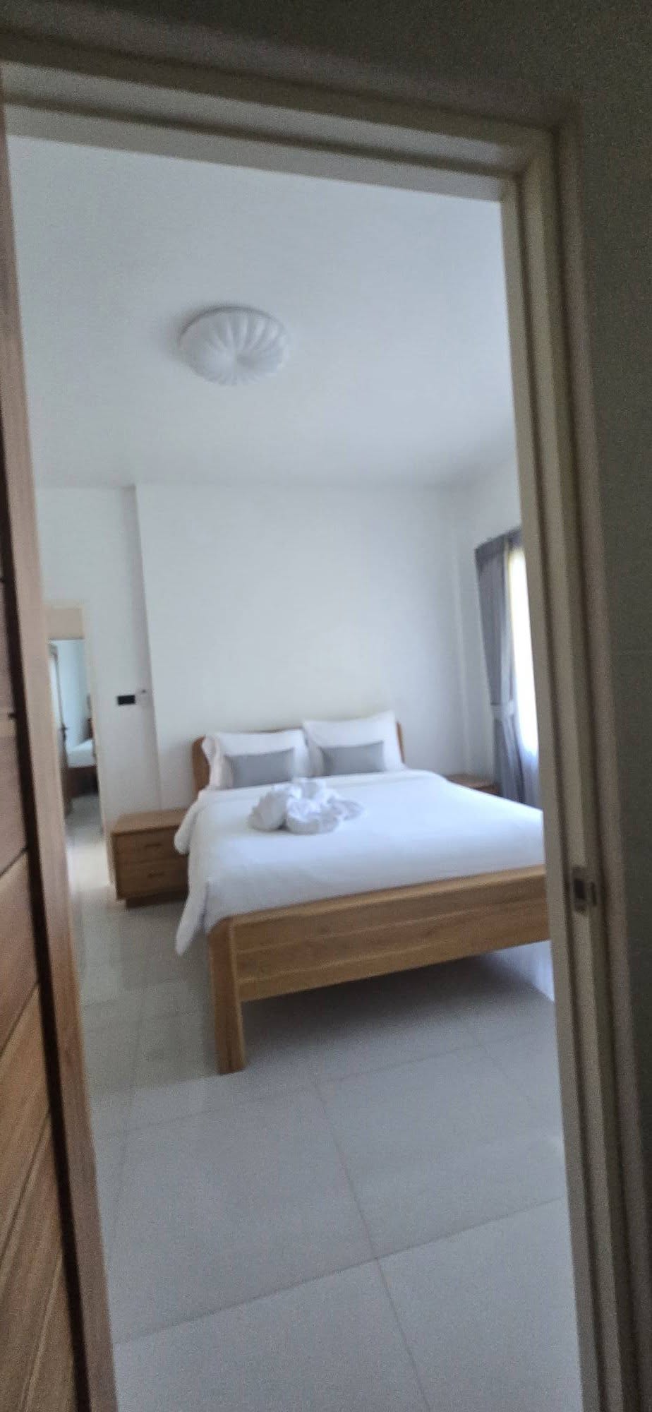 Master bedroom with wood bed frame, white linens and soft natural light