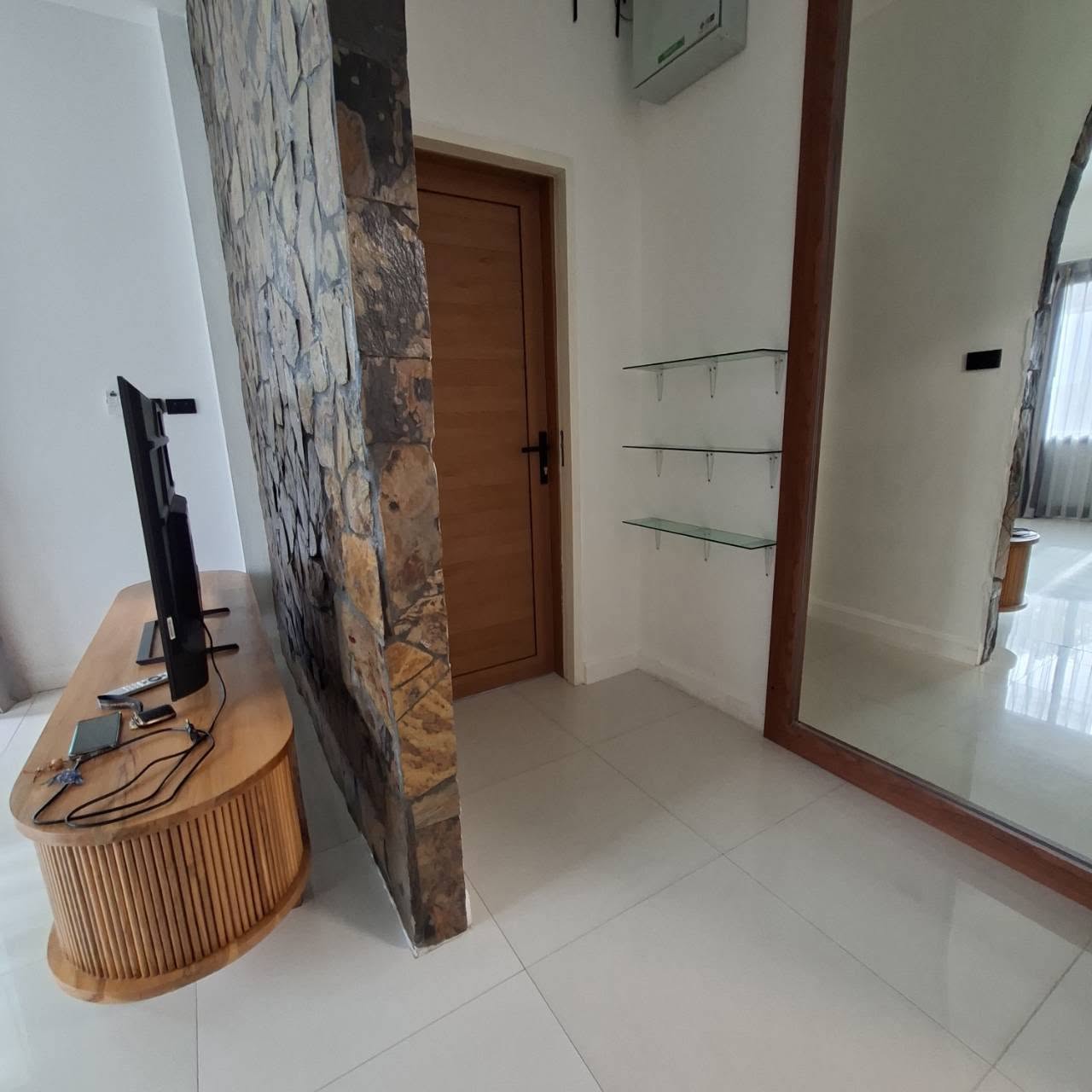 Living room corner with stone accent wall, media console and floor mirror